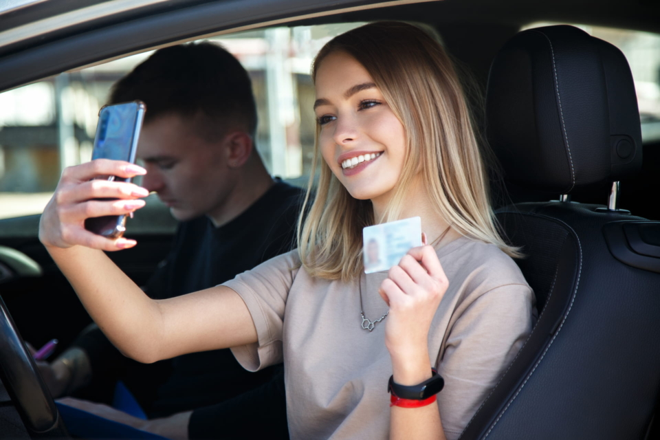 Junge Frau macht Selfie mit Führerschein